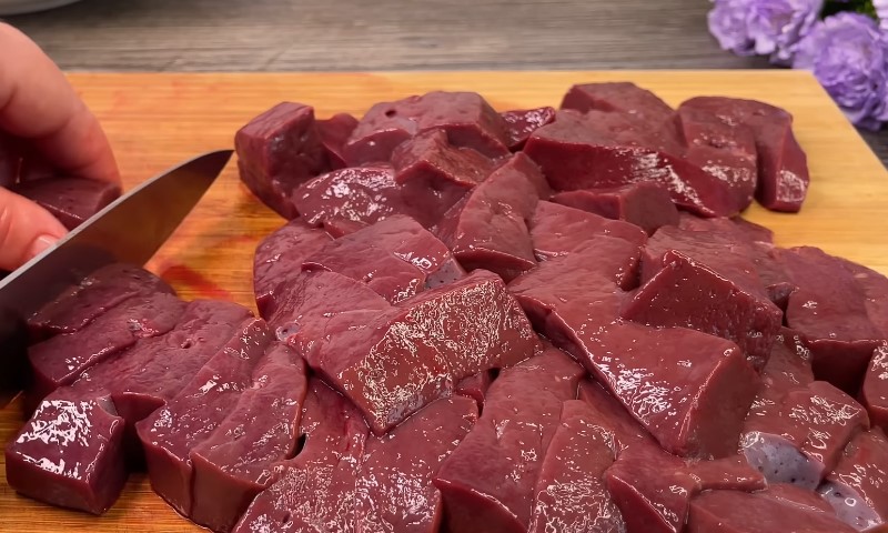 Оsoba seče goveđu džigericu na dasci za sečenje