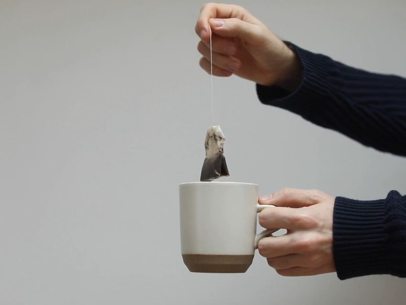 devojka drži šolju čaja i kesicu čaja u ruci