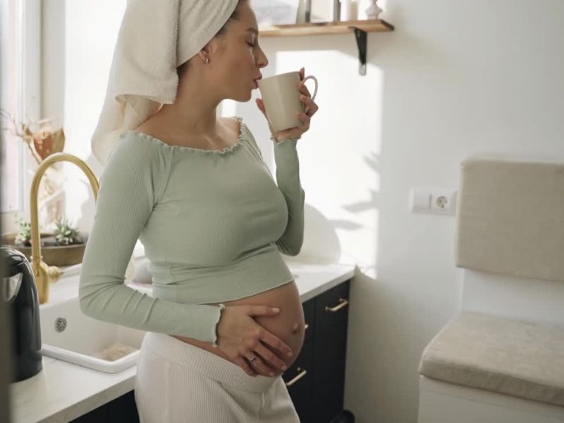 trudnica sa peškirom na glavi pije čaj